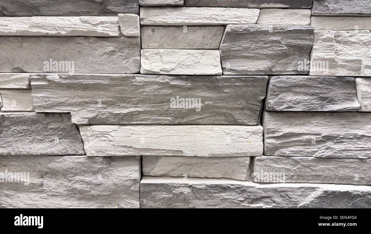 Gray stone wall texture in close-up with layered masonry pattern and rough surface. Stock Photo