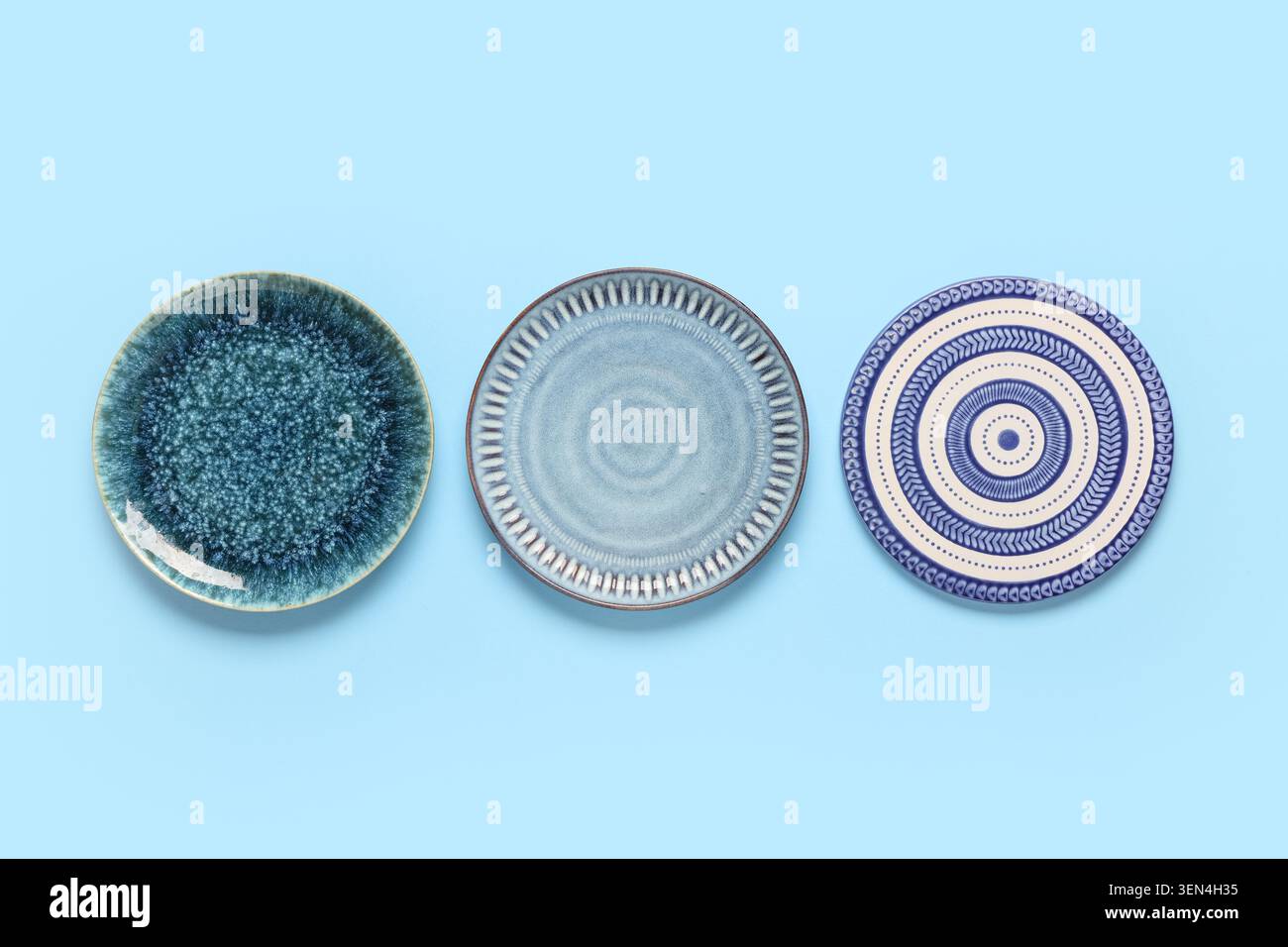 Three ceramic plates with unique textures and patterns on a light blue background, kitchenware and tableware design, this collection represents modern Stock Photo