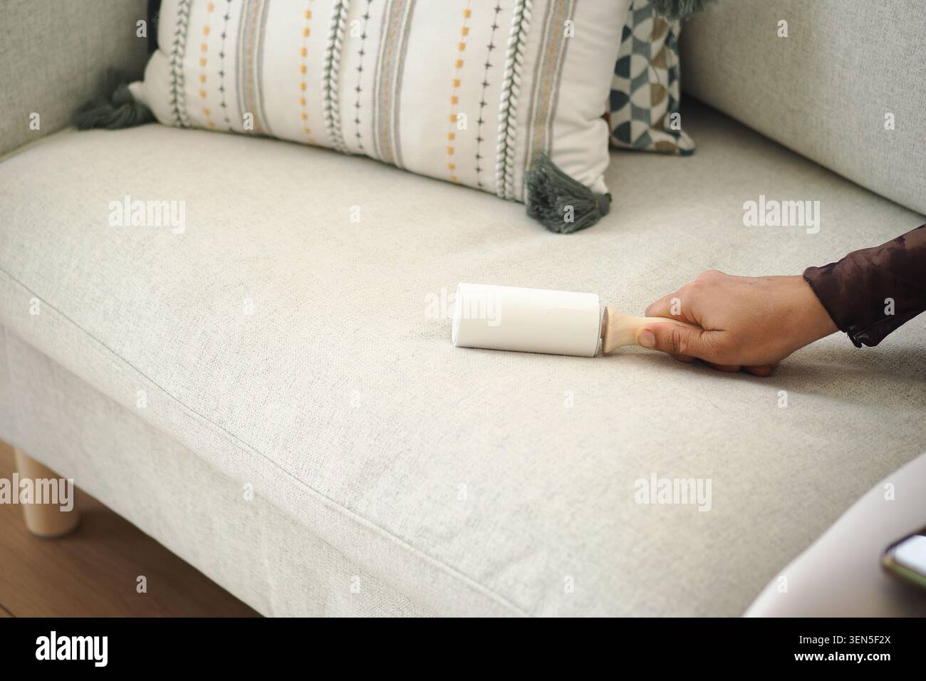 Cleaning lint from a couch with a lint roller Stock Photo