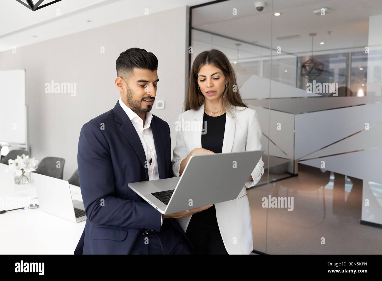 Colleagues using laptop analyzing data together in office Stock Photo