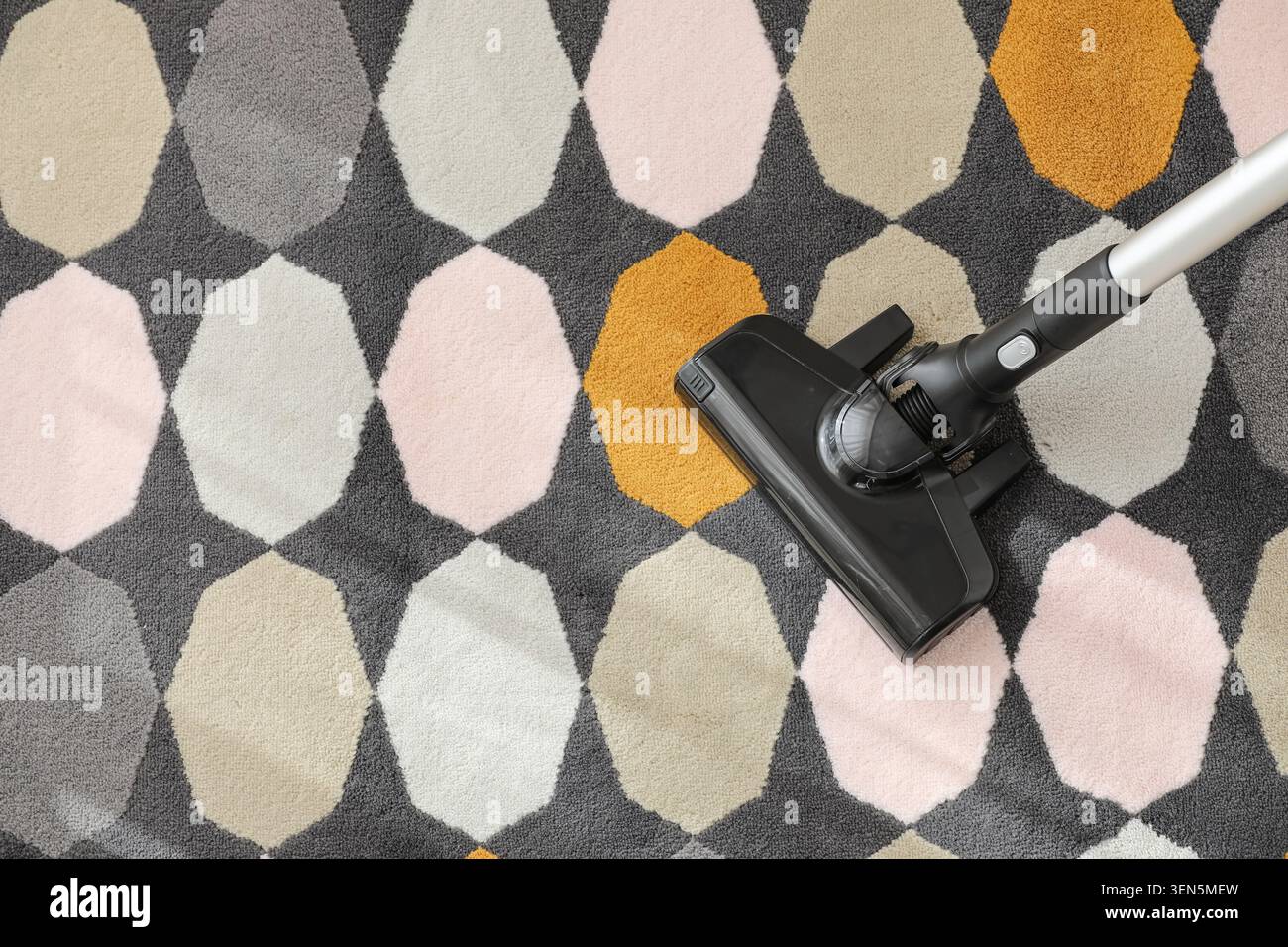Vacuum cleaner head cleaning modern geometric patterned carpet, home chores and domestic cleaning service Stock Photo