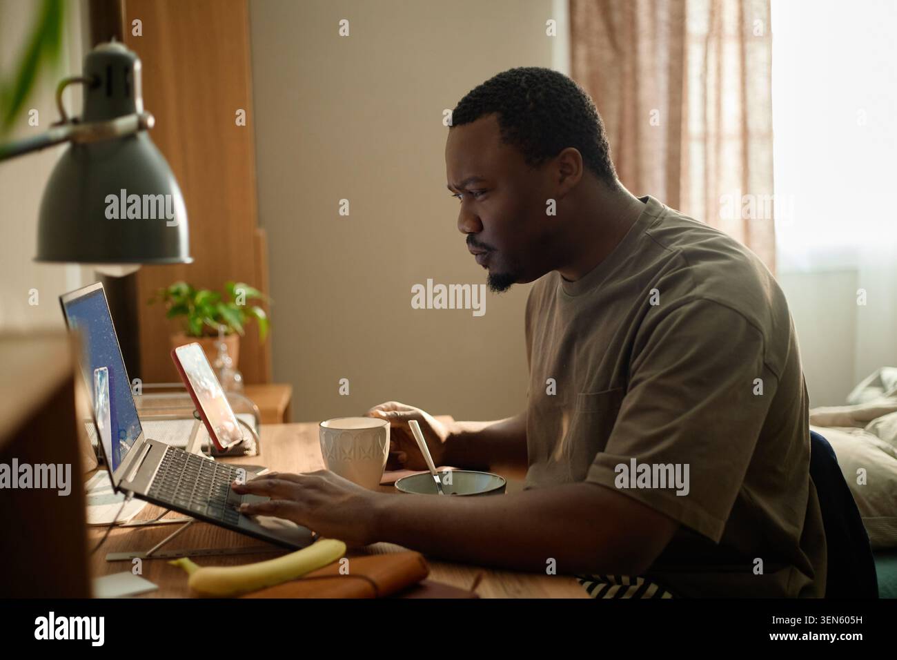 Black Man Using Laptop while Working from Home Stock Photo