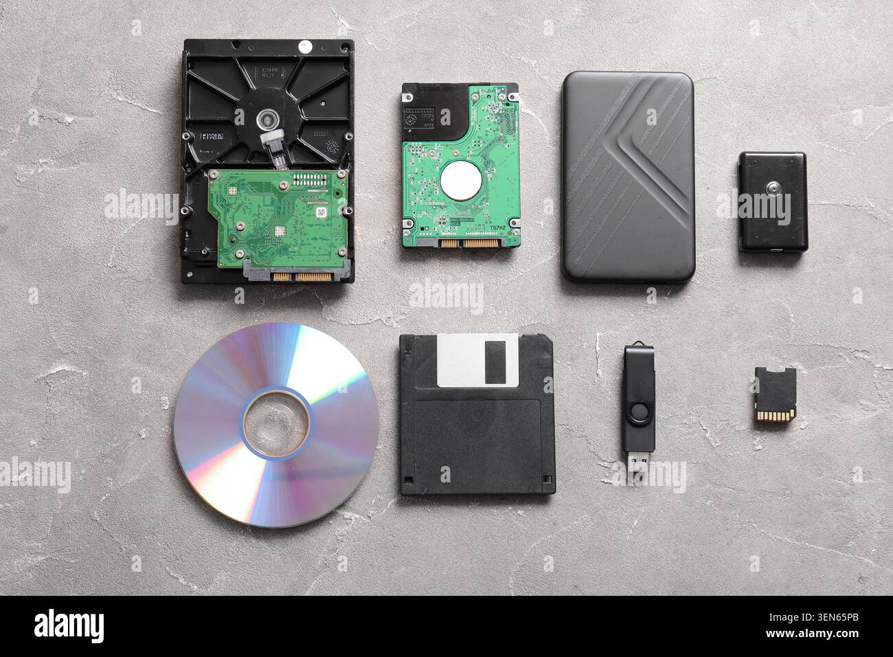 Evolution of data storage devices: hard drives, floppy disk, CD, USB flash drive, and memory card on gray background Stock Photo