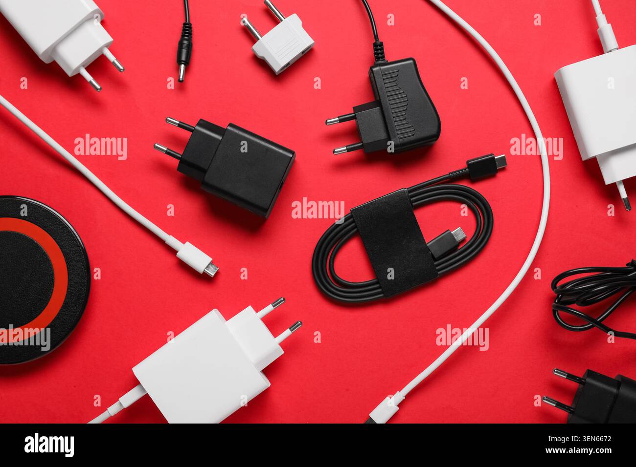 Assorted electronic device chargers and cables for modern technology on red background Stock Photo