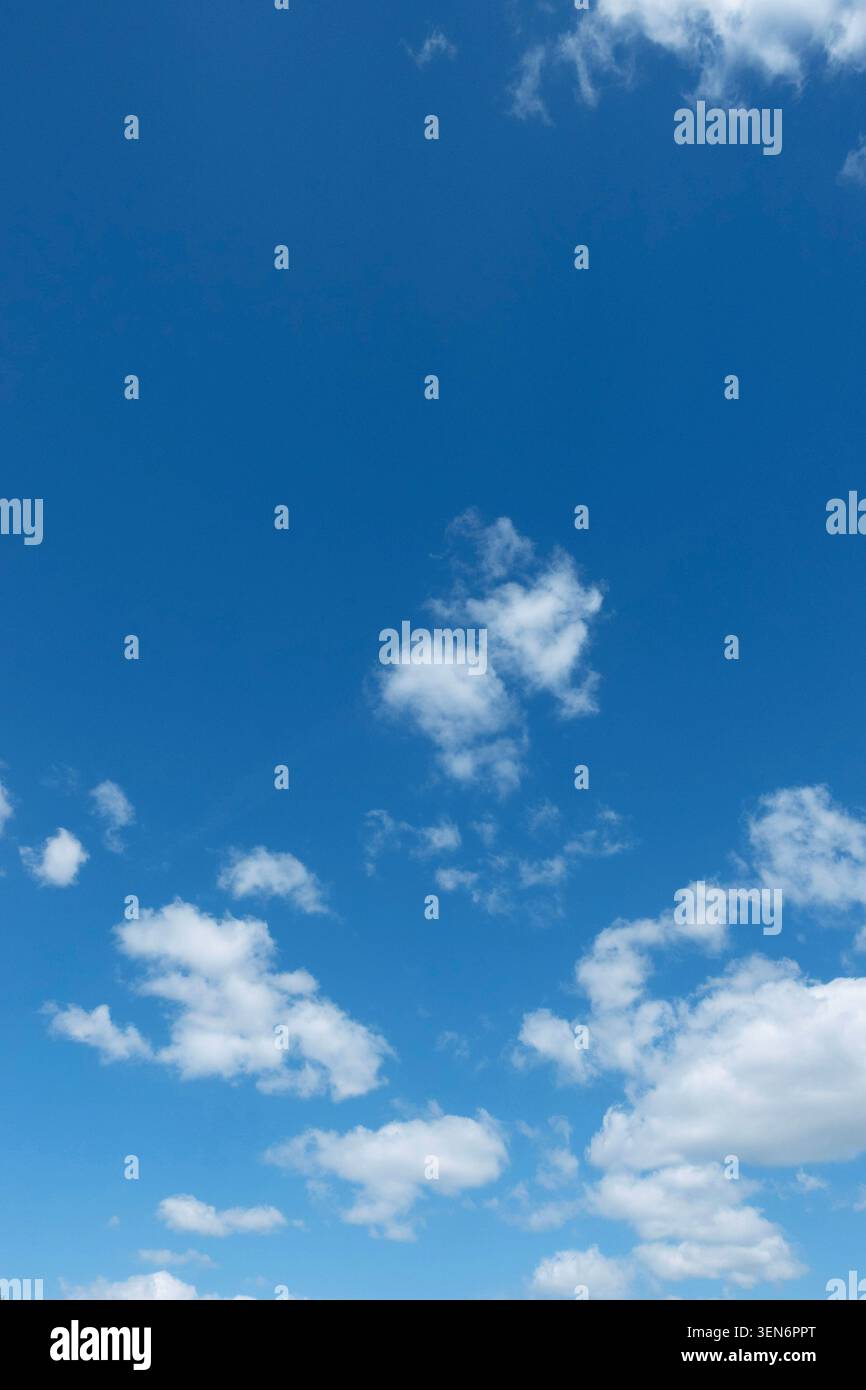 Blue summer sky with scattered white clouds, a peaceful weather background with copy space and natural daylight Stock Photo