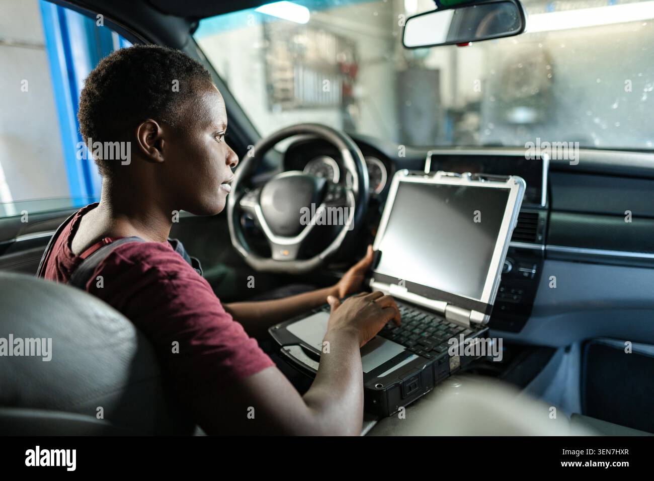 Young female mechanic running diagnostics on a car with a laptop Stock Photo
