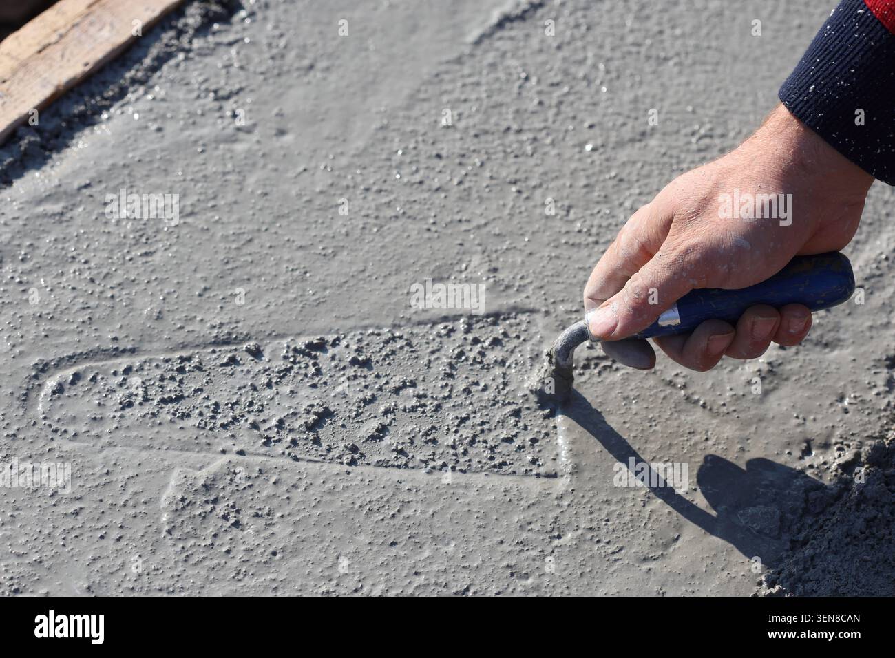 A worker spreading mortar evenly using a trowel Stock Photo