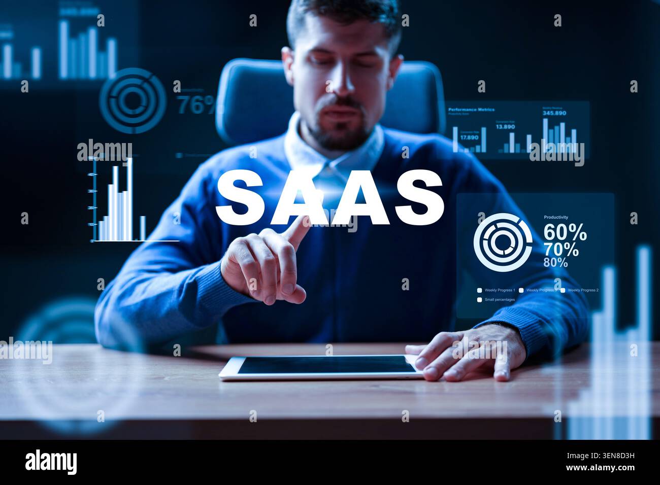 Man interacts with SaaS interface on tablet in office setting during evening hours Stock Photo