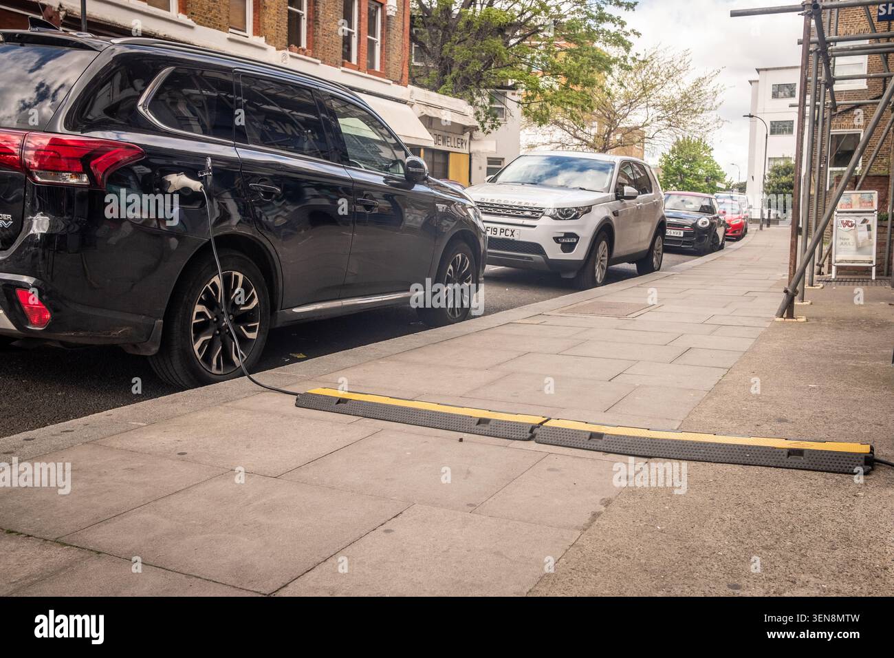 LONDON - APRIL 18, 2026: HAMMERSMITH – EV charging cable across pavement Stock Photo