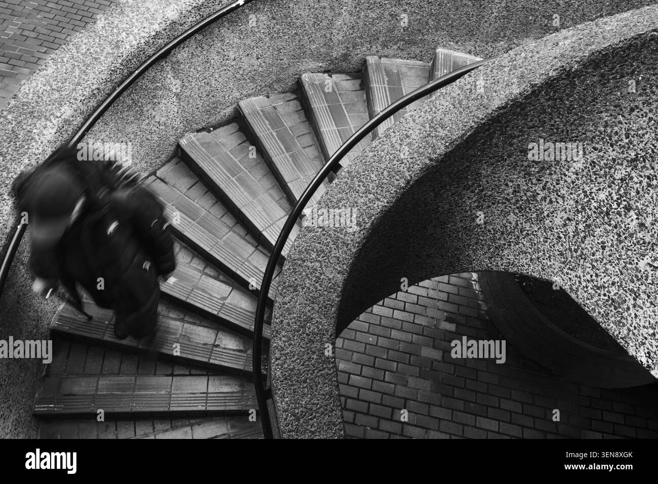 A man walking down some spiral stairs Stock Photo