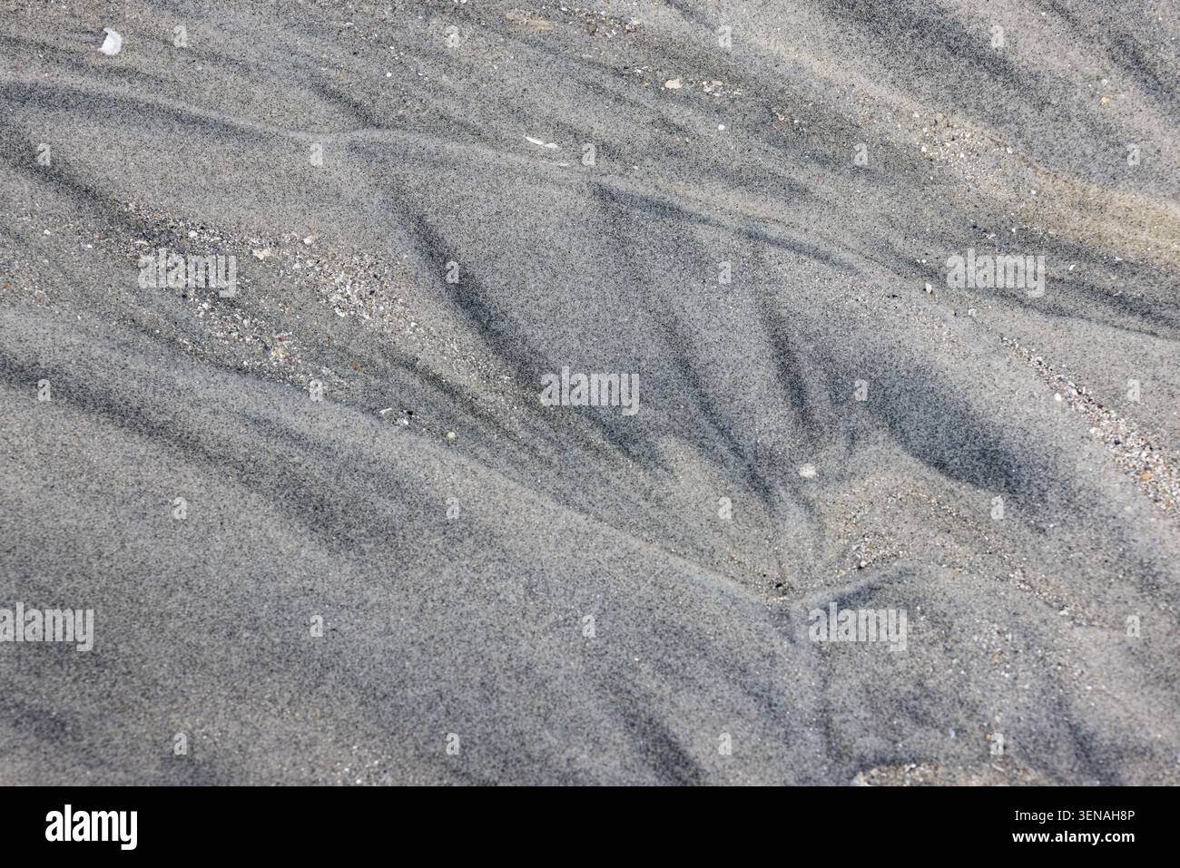 Black and gray pattern in the sand on a sandy beach, background Stock Photo