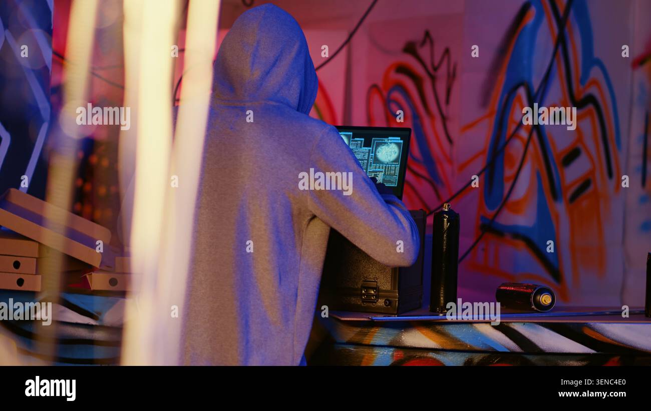 Close-up shot of hacker in underground bunker using network vulnerabilities to exploit servers, trying to break computer systems at night, African American cybercriminal breaching networks. Stock Photo