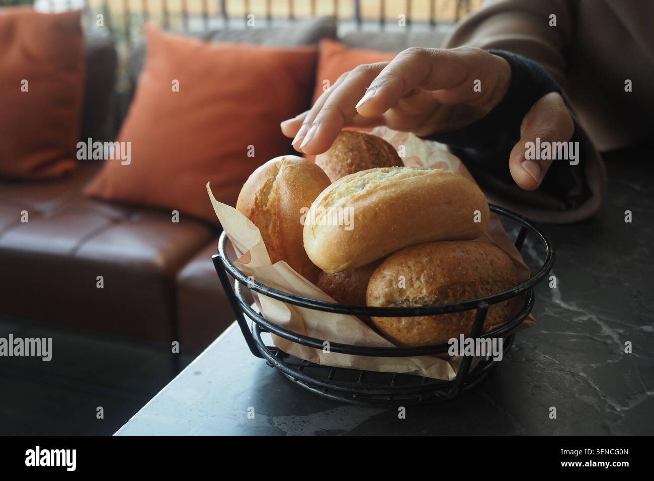 Hand reaching for bread rolls in a cafe setting Stock Photo