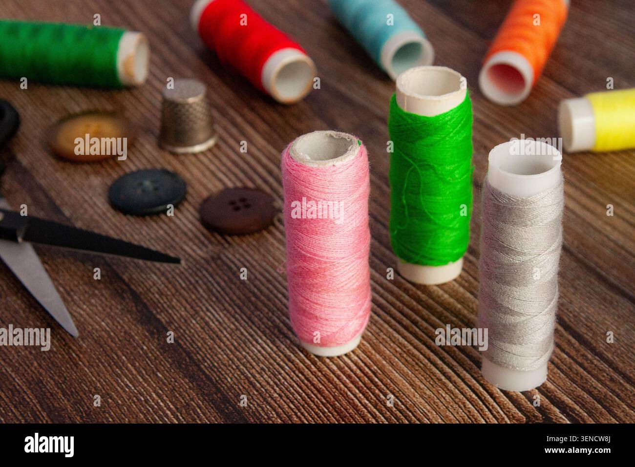 Sewing Thread Spools With Buttons And Scissors On Wooden Table Stock Photo