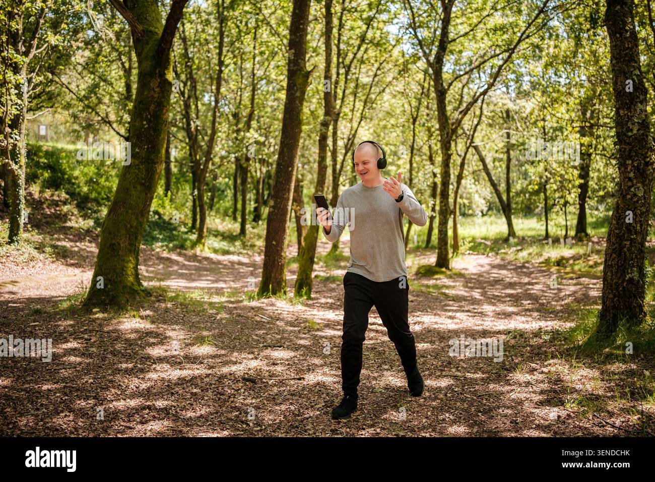 Man wearing headphones and holding smartphone while videoconferencing outdoors Stock Photo