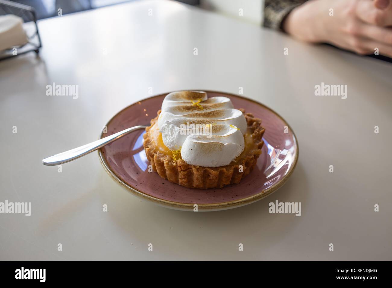 Lemon meringue tart on a pink plate with spoon Stock Photo