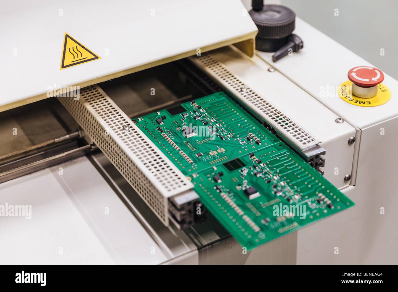 Printed circuit board moves through industrial electronics manufacturing machine Stock Photo