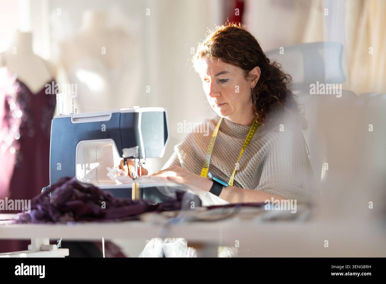 Sewing in a studio during daylight while focusing on fabric and patterns Stock Photo
