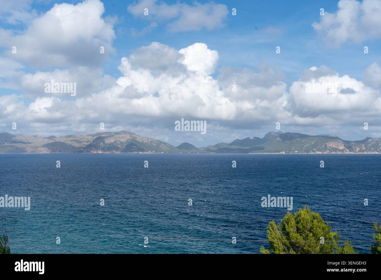 Dramatic cloudscape over deep blue sea and distant mountain coastline Stock Photo