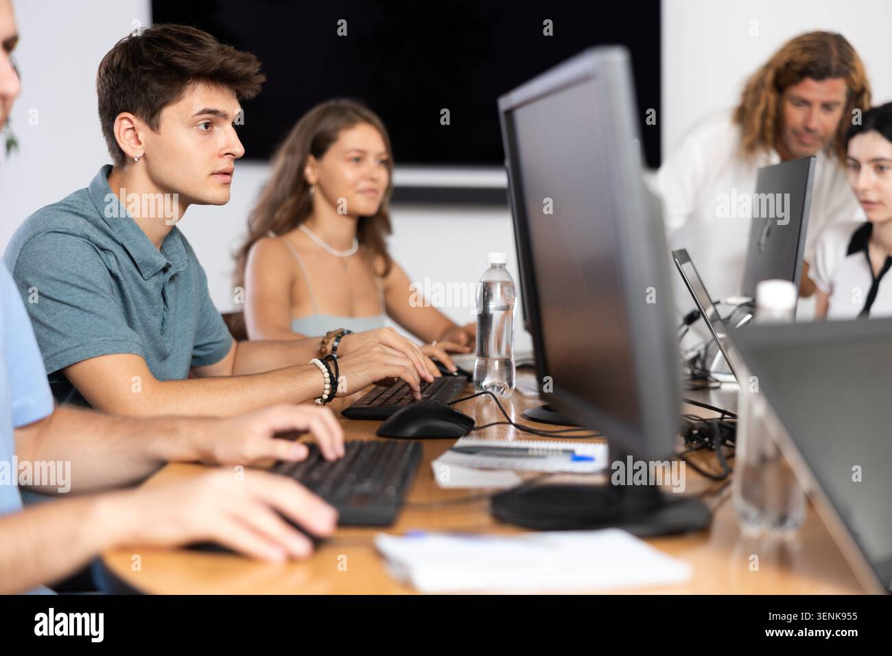 Focused guy studying in computer lab with fellow students Stock Photo