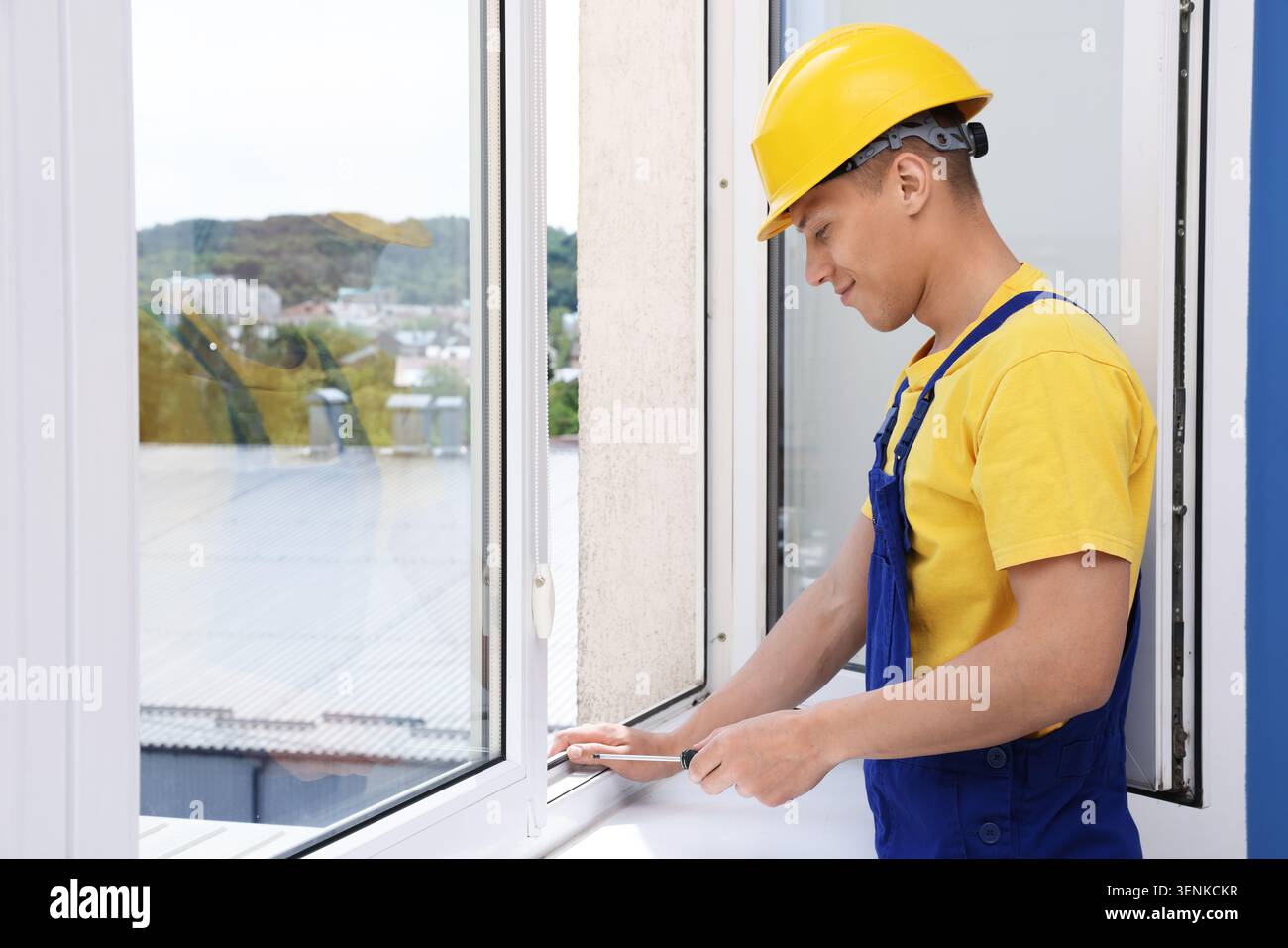 Professional worker with screwdriver installing window indoors Stock Photo