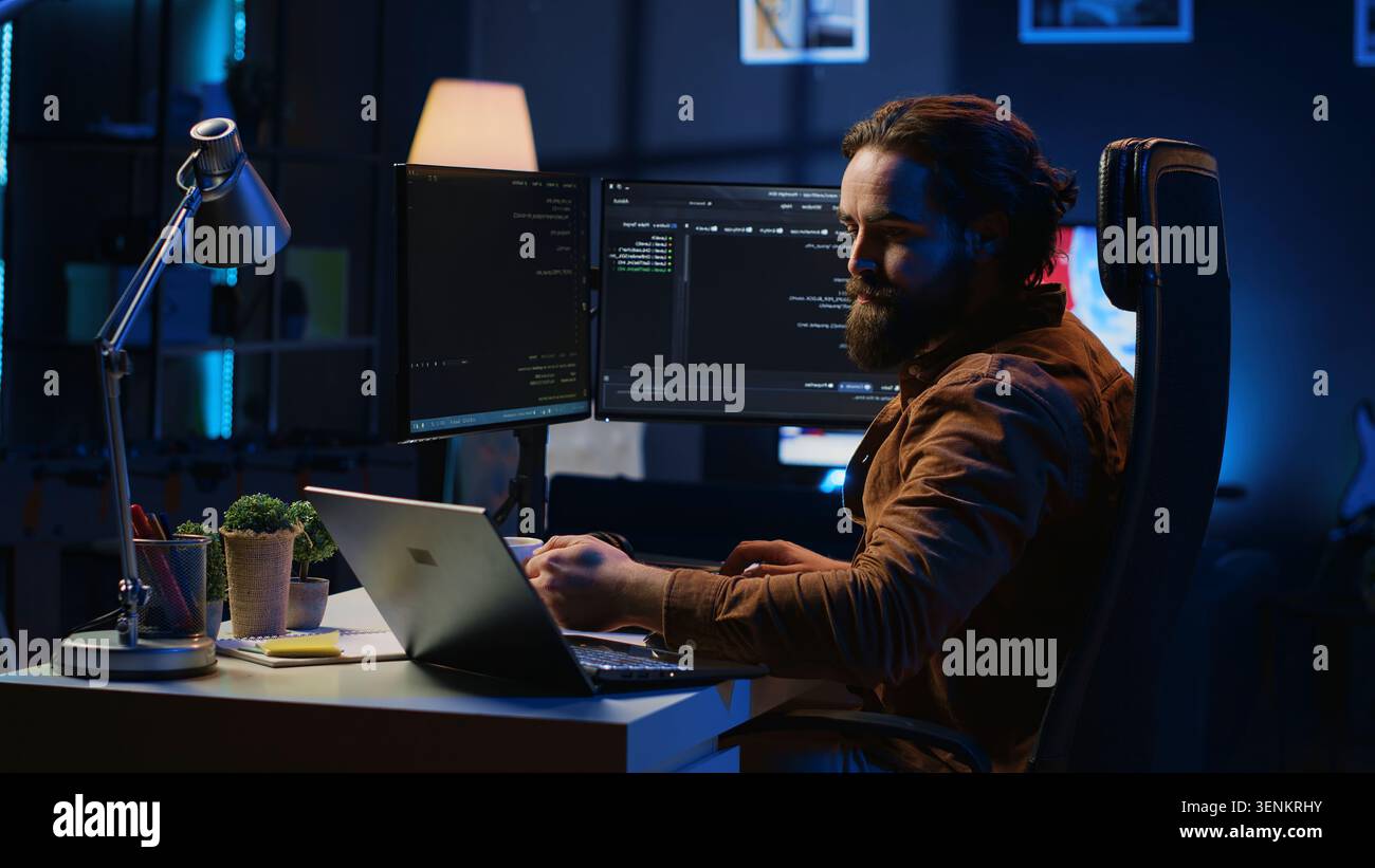 Software programmer putting headphones on while developing code, making time pass faster during remote job shift. Stock Photo