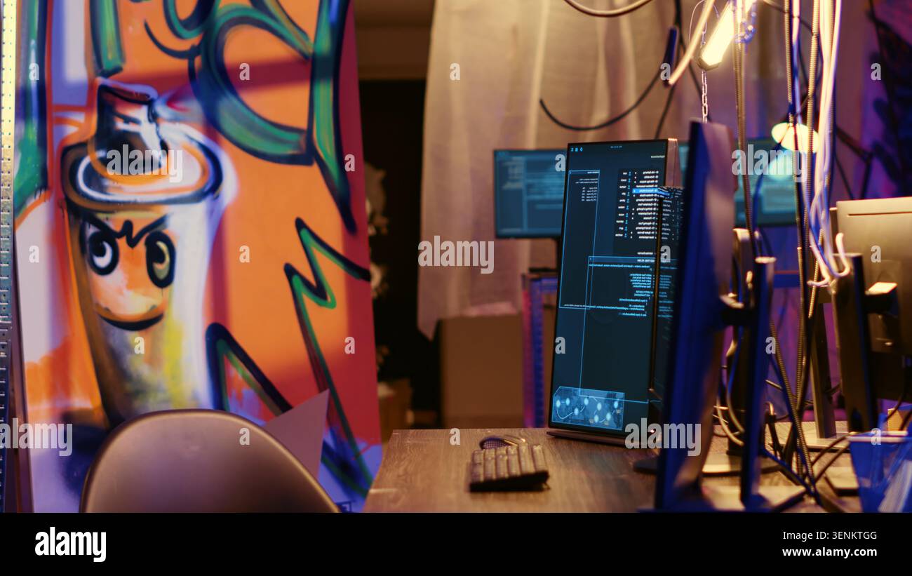 Graffiti painted empty hideaway base with lines of code running on computer screen with malware that get past security systems. PCs in deserted bunker showing scripts that can hack devices. Stock Photo