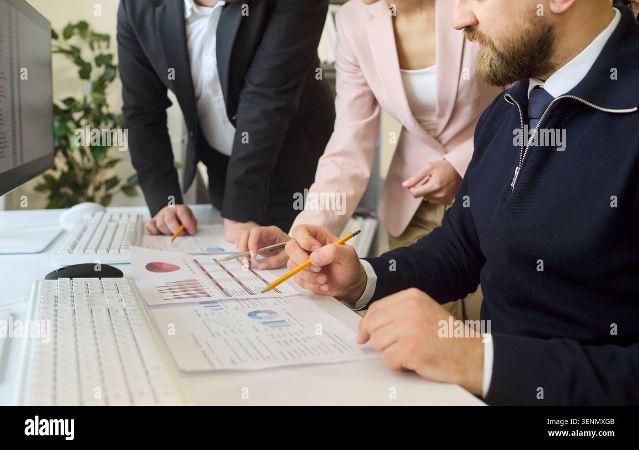 Business team analyzing financial charts at desk with pencils and computer Stock Photo