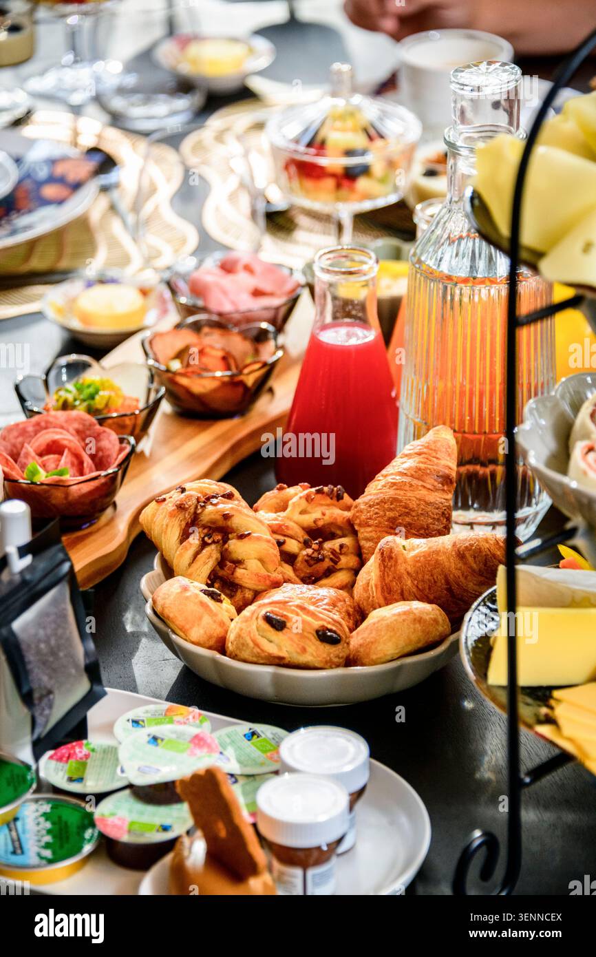 Lavish breakfast buffet with croissants, pastries, cold cuts, juice and cheese. Abundant hotel brunch spread with warm inviting tones. Stock Photo