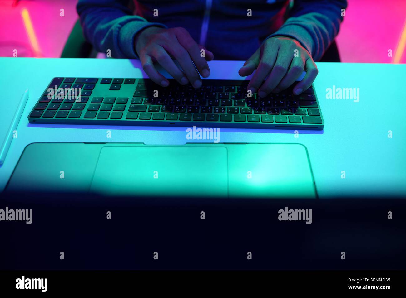 Hands Typing on Keyboard Under Neon Light Stock Photo