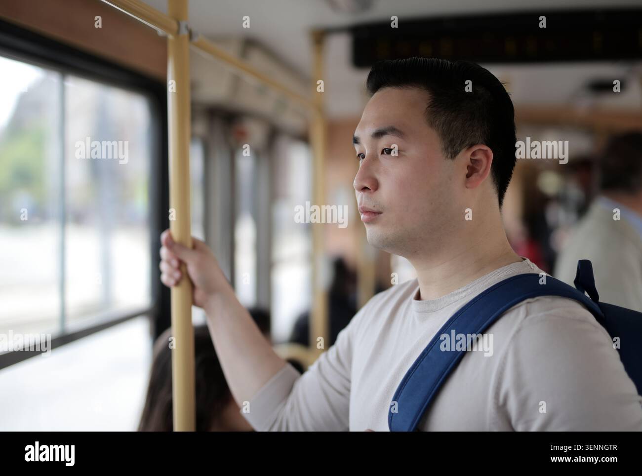 Young Asian man looking out a bus window Stock Photo