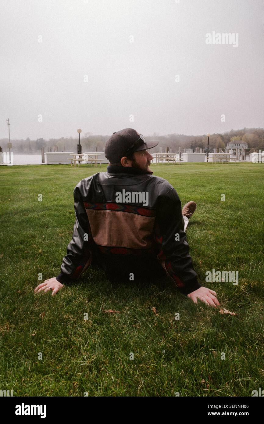 Man in a leather jacket relaxes on grass Stock Photo