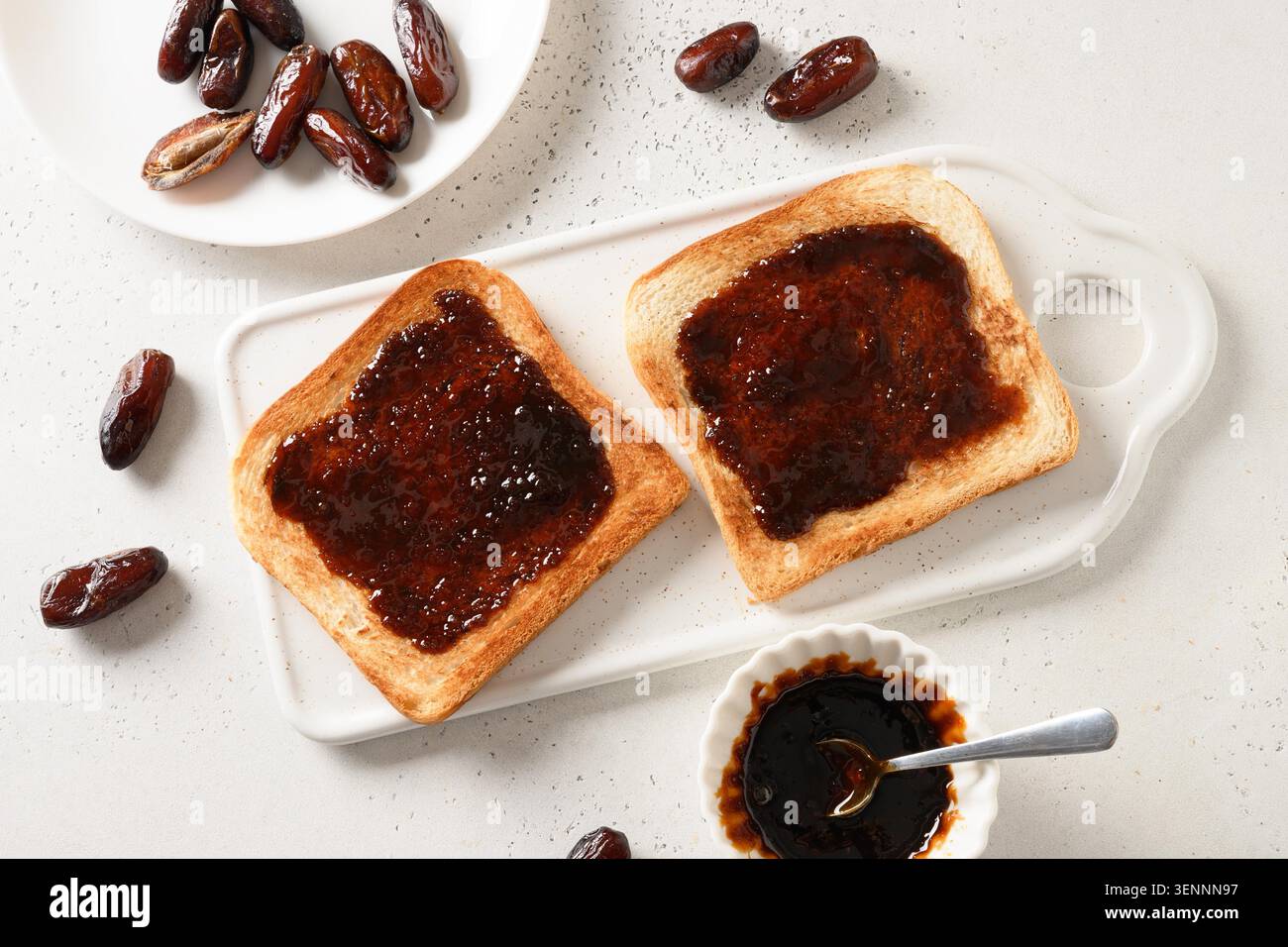 Fresh crispy toasts with dates jam without sugar on white table. View from above. Healthy vegan sweets. Stock Photo