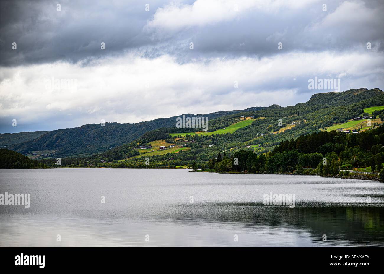 A lake is a calming view up in the mountains, rural areas are stretching down the hills Stock Photo