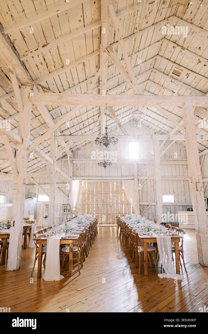 Rustic wedding dinner setup in white wooden barn Stock Photo