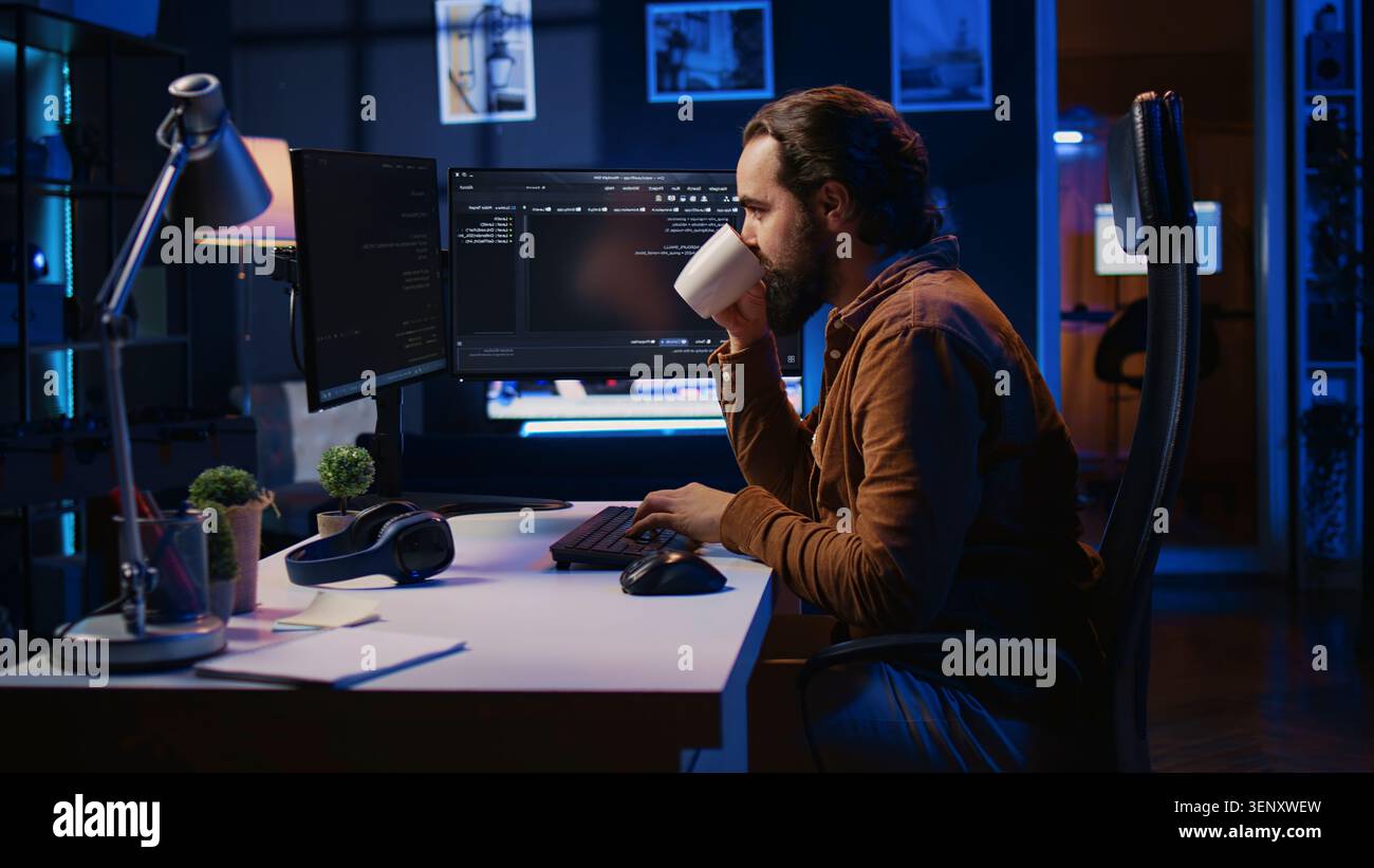 Focused programmer drinking coffee in apartment while solving database errors on computer, remotely working IT admin concentrated on finalizing coding project in home office. Stock Photo