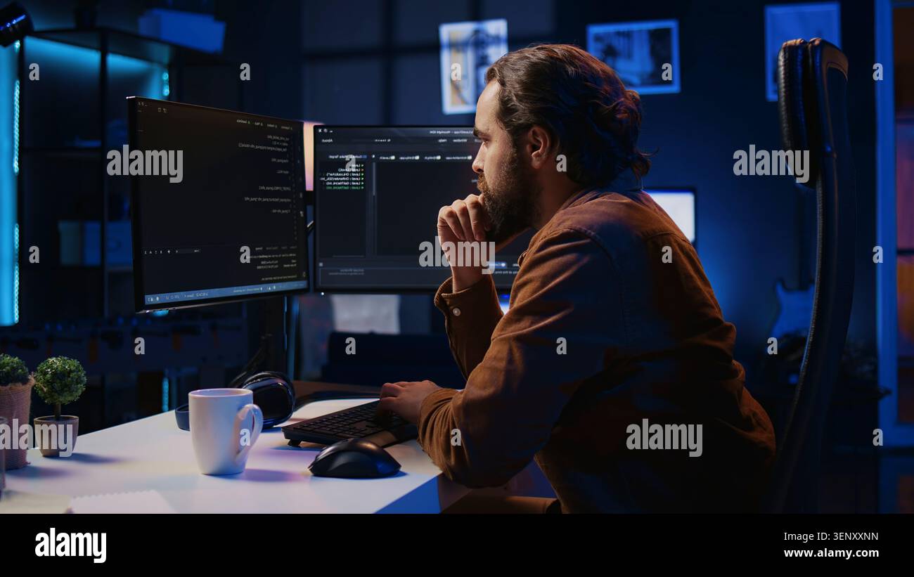Programmer doing web development during remote job shift in neon lit home office, finishing coding project, IT specialist sitting at computer desk, working on desktop PC. Stock Photo