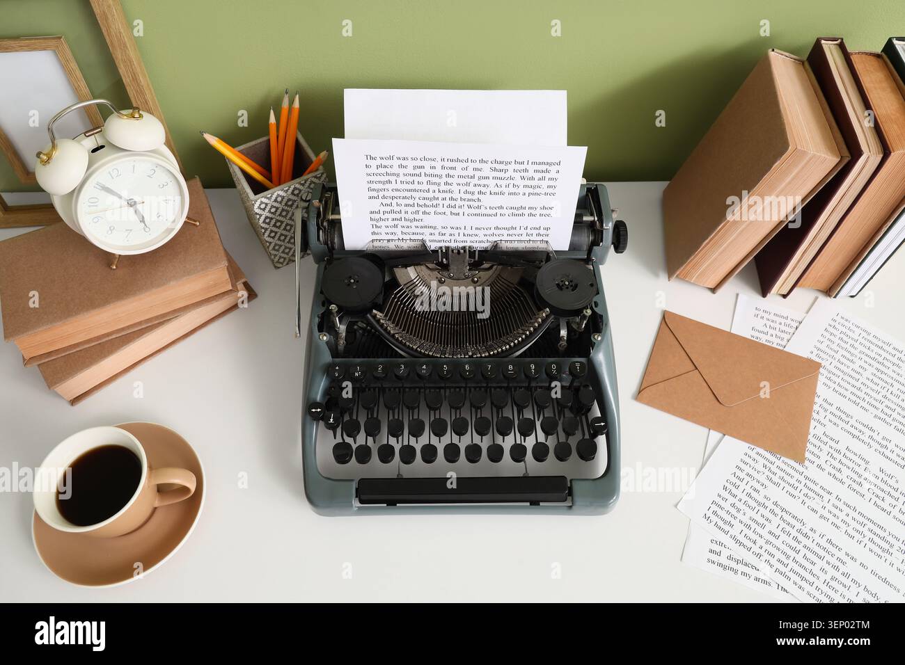 Vintage typewriter with blank paper, books, alarm clock, and coffee cup on white desk for creative writing Stock Photo
