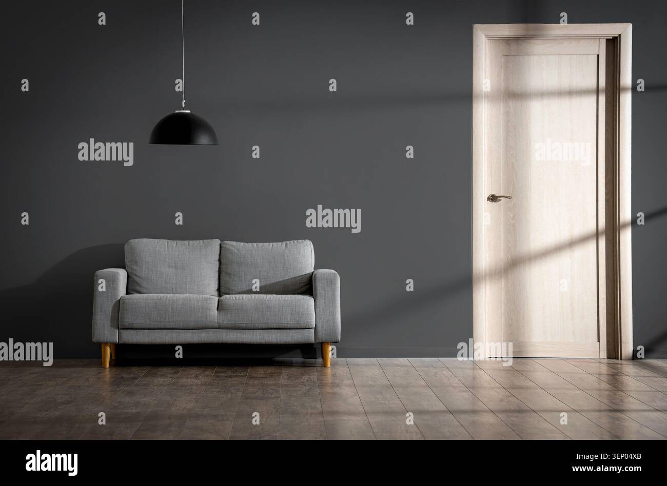 Modern minimalist living room interior with gray sofa, black pendant lamp, and wooden door on dark wall Stock Photo