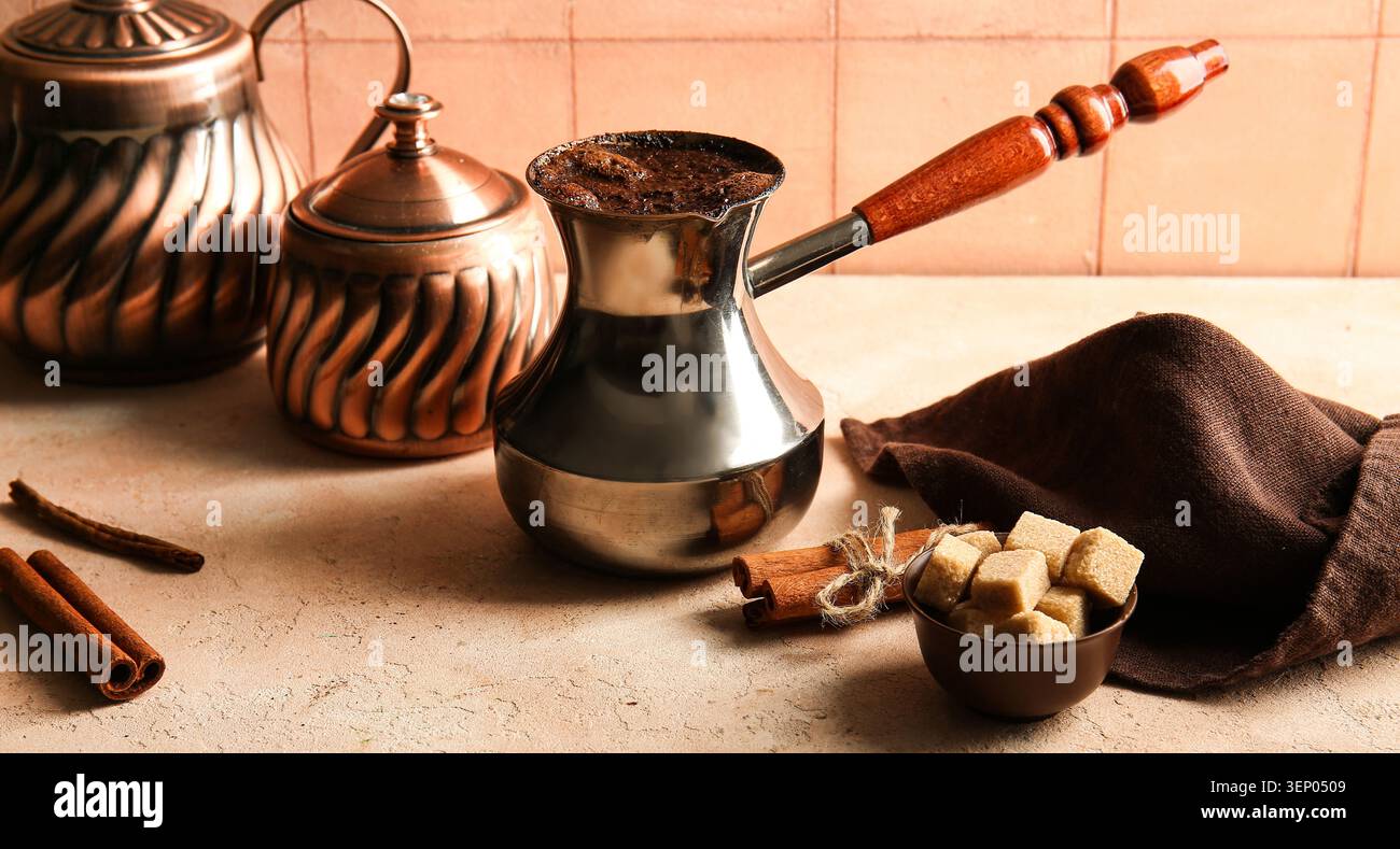 Traditional turkish coffee pot with freshly brewed coffee, cinnamon sticks, and brown sugar cubes Stock Photo
