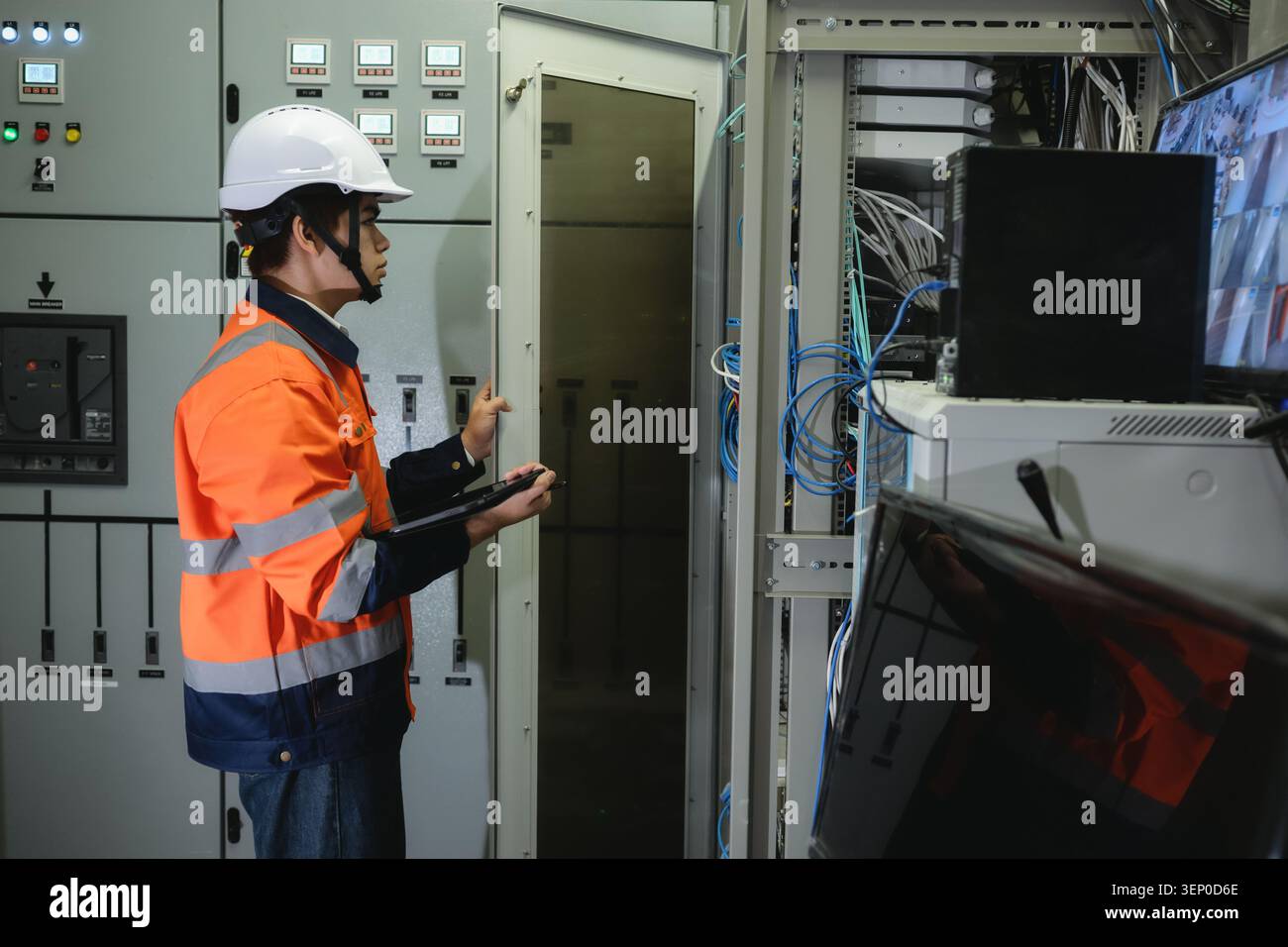 Asian young IT engineer in uniform using tablet and open to server rack cabinet, Systems engineer in safety gear examines server equipment, Configurin Stock Photo