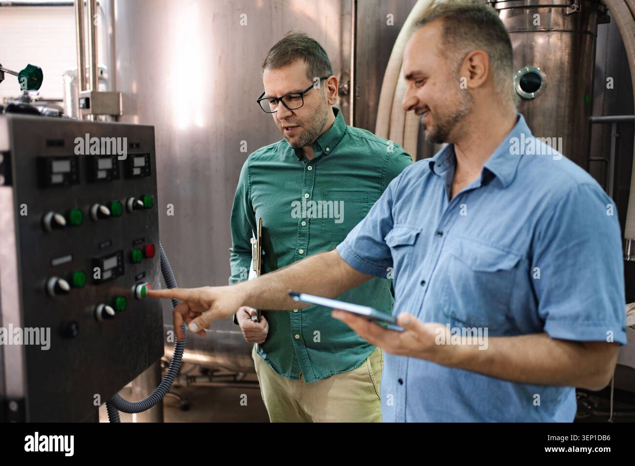 Brewery workers operating control panel in production facility Stock Photo