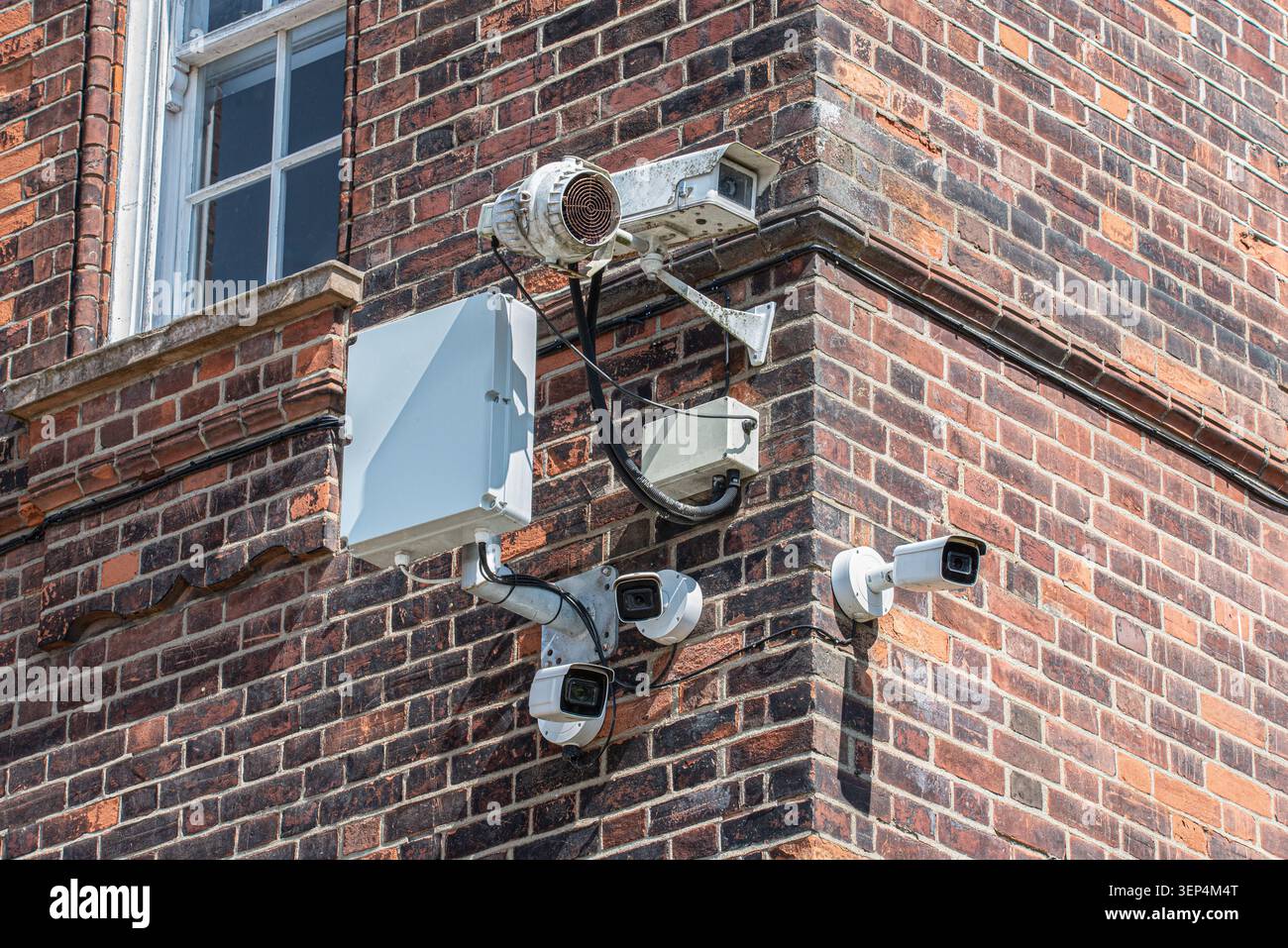 Multiple CCTV security cameras installed on the corner of a red brick building, representing urban surveillance, monitoring, and safety infrastructure Stock Photo