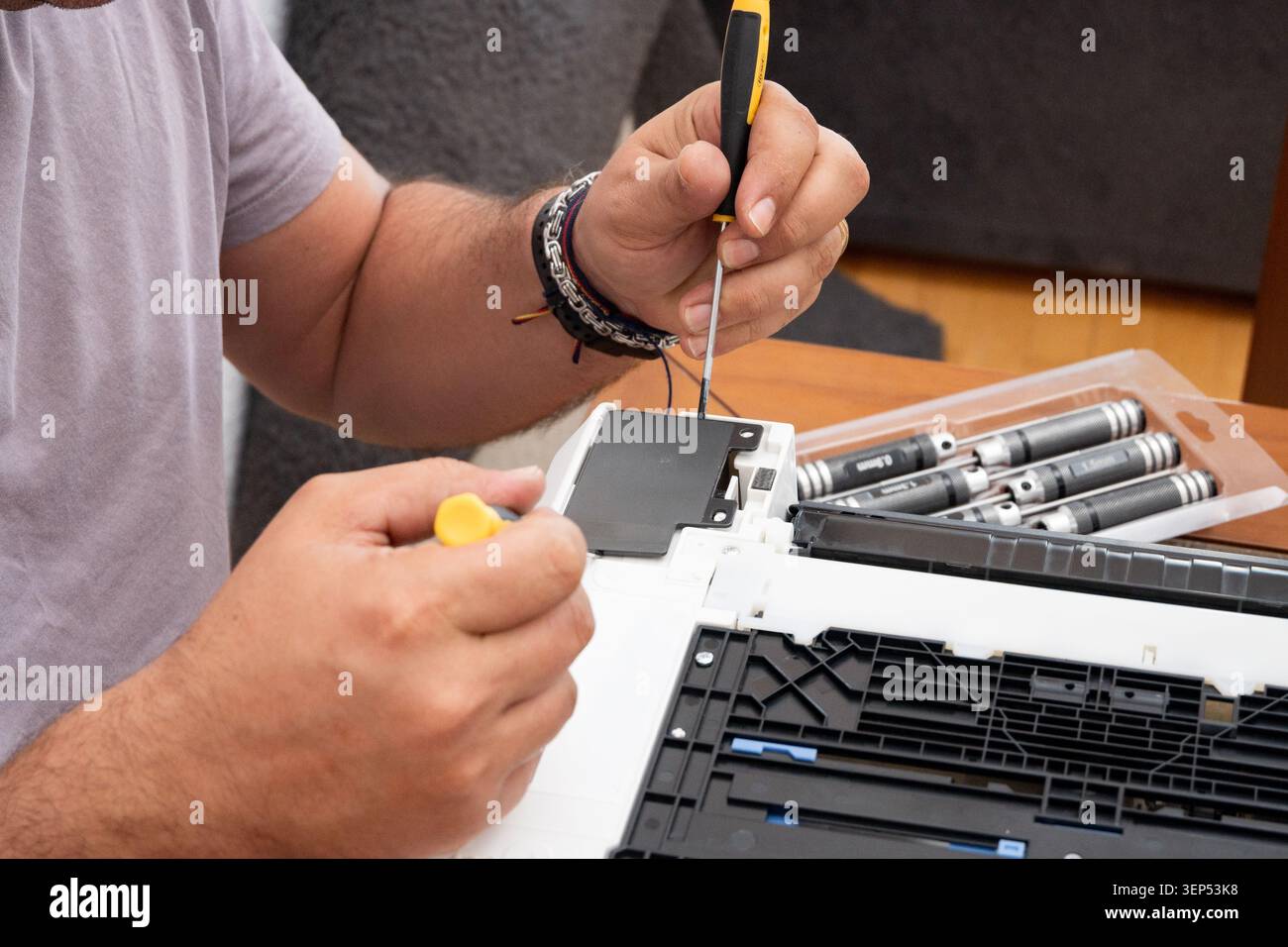 Man repairing electronics, focusing on disassembling a device with tools Stock Photo
