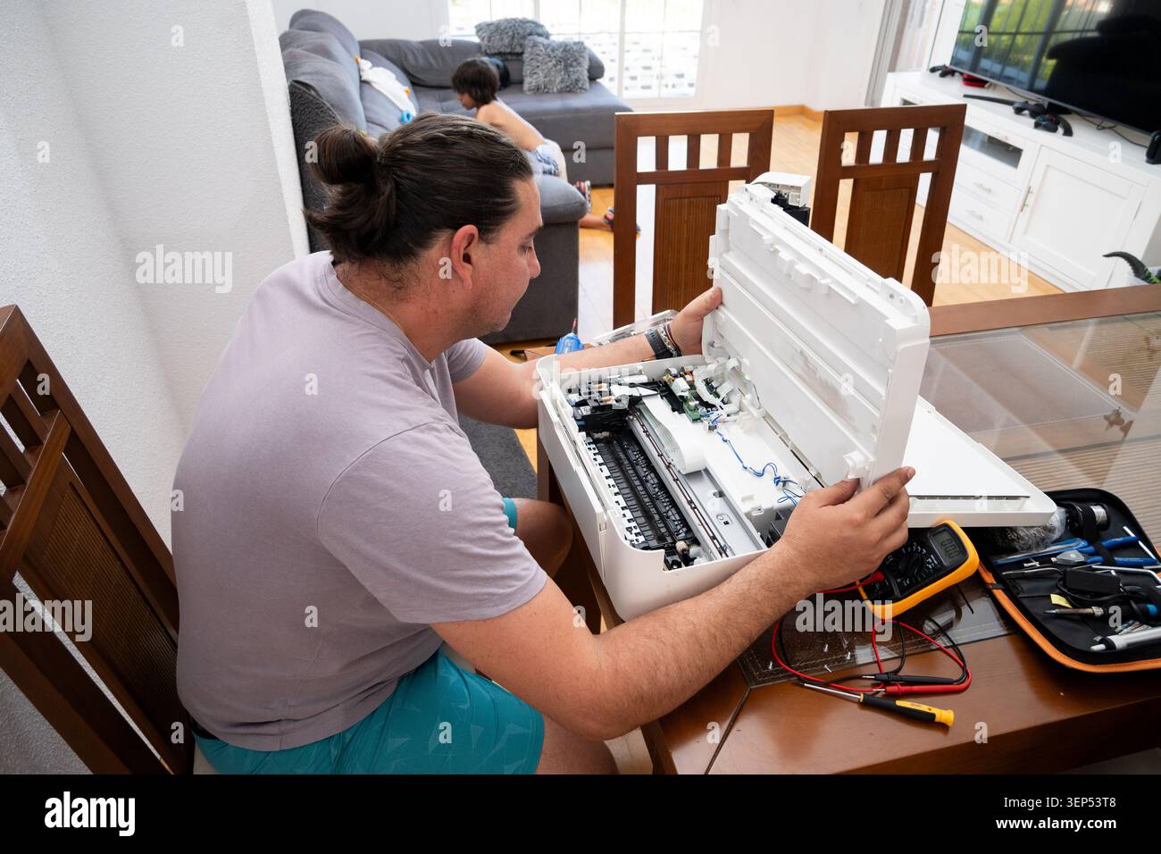 Man opening a printer case and using tools for home repair Stock Photo