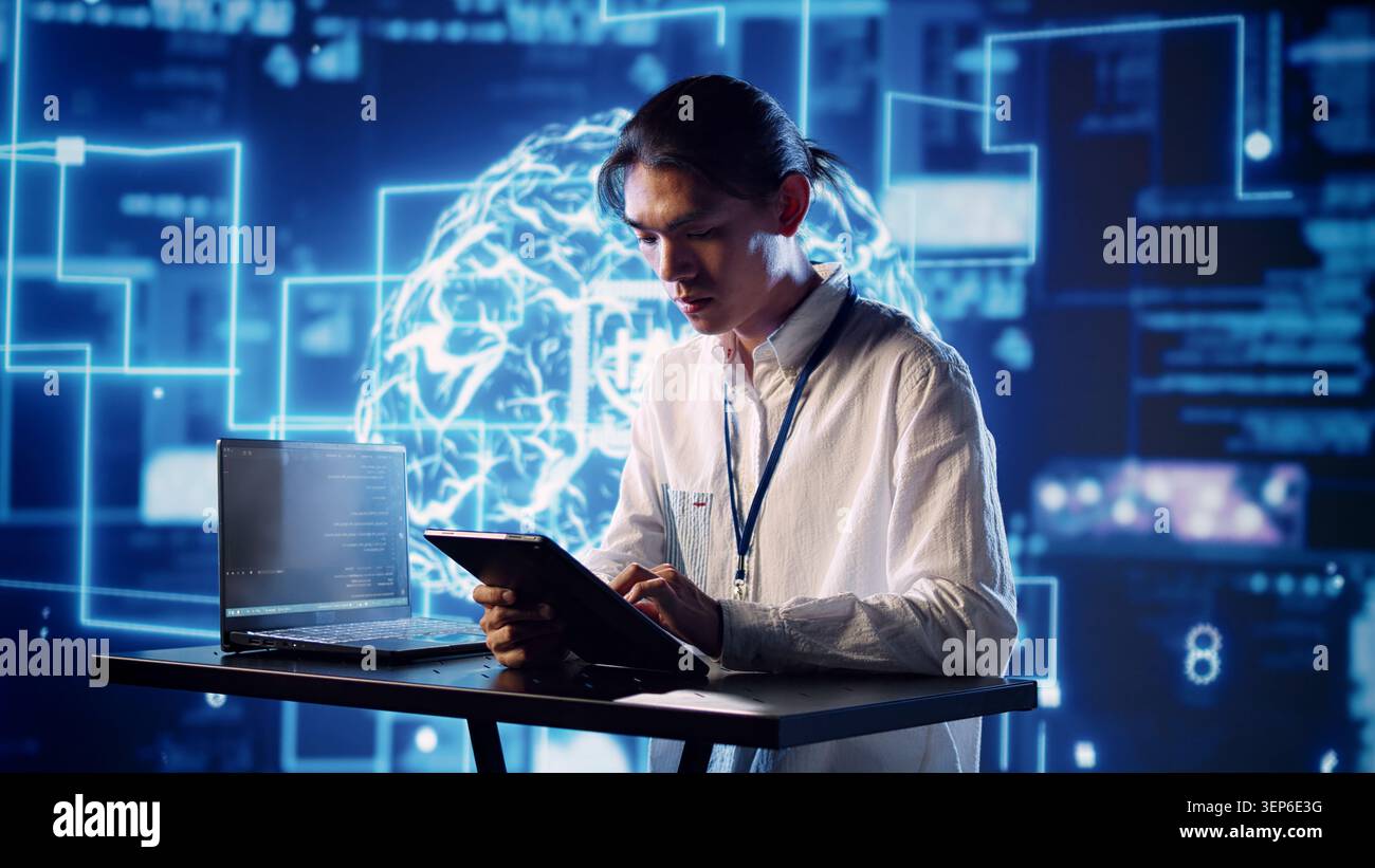 Productive engineer in high-tech workspace uses artificial intelligence computing simulating human brain, admin in server farm running operations on laptop with AI machine learning algorithms. Stock Photo