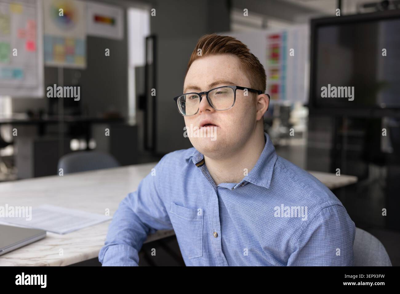 Young man with Down syndrome in modern office Stock Photo