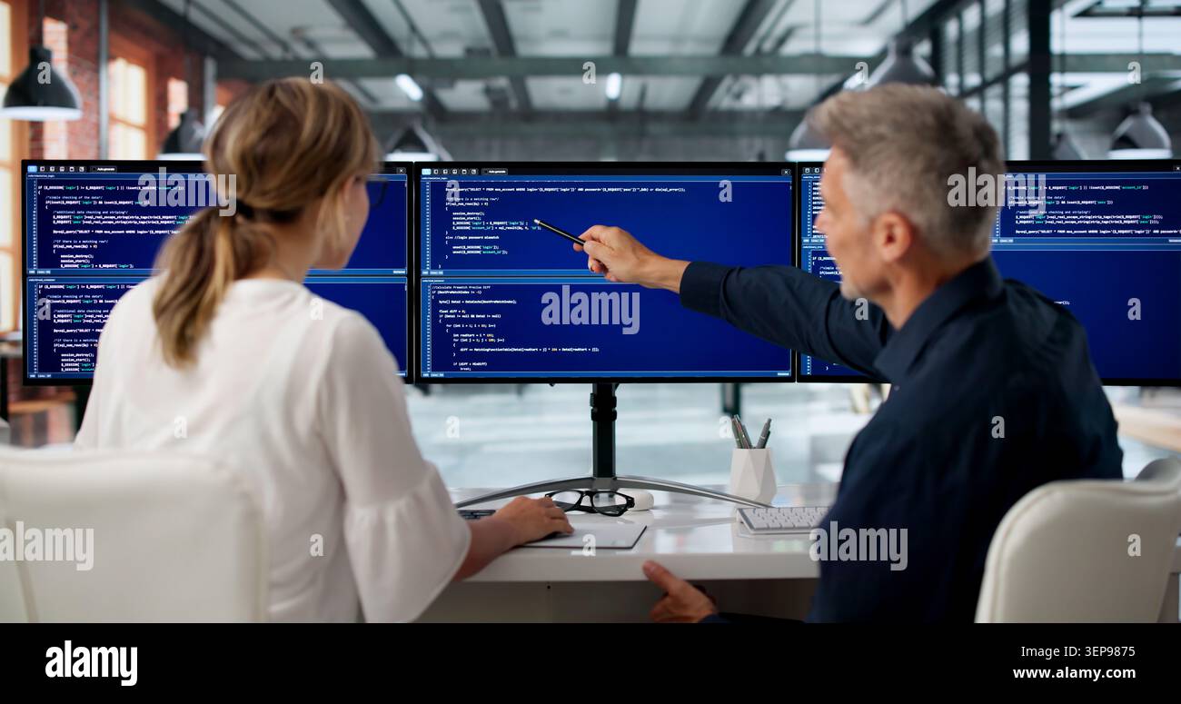 Two Software Engineers Work Side By Side Coding Secure Web Applications Together. Stock Photo