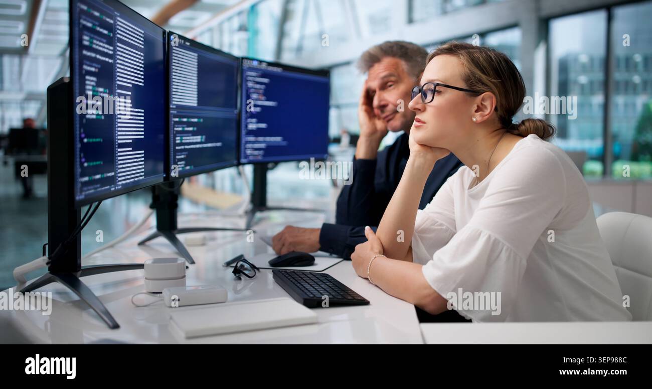 Frustrated Developers Face Coding Mistakes While Working Late In Quiet Office. Stock Photo