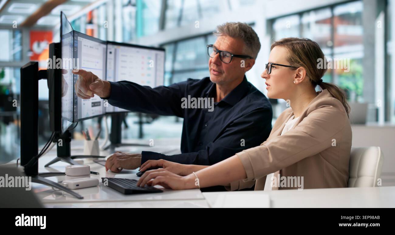 Two Office Workers Analyze Digital Document Workflow System On Computer Screen. Stock Photo
